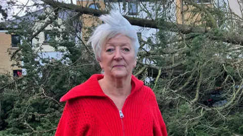 Ann Glasgow in red top with fallen tree in background 