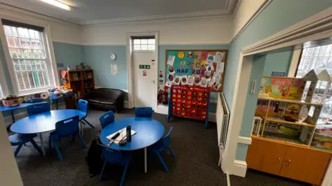 A room with circular blue tables and chairs with dated light blue walls