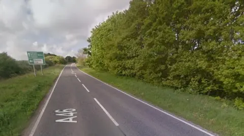 A straight section of the A46. Trees flank the road on both sides.