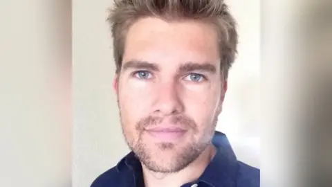 Supplied Darryn Frost is wearing a navy blue shirt and has a beard with dark blond hair