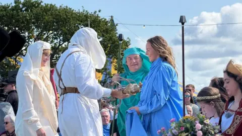 People in white, blue and green robes speak