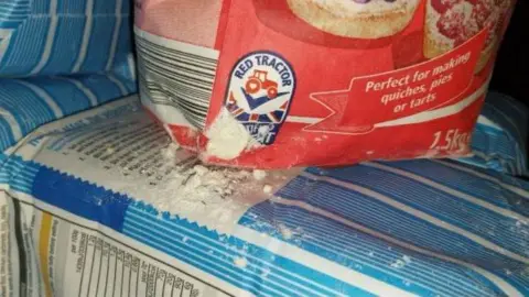 Gloucester City Council A ripped red bag of flour spills over the top of a blue bag of food after being gnawed at by mice