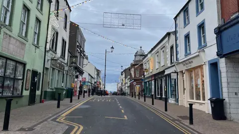 Federica Bedendo/BBC A general view of Senhouse Street in Maryport. It is lined by shops and pubs and has a bus stop on one side of the one-way street.