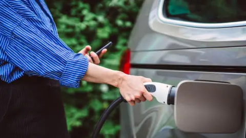 A close-up of a young woman charging her electric car.