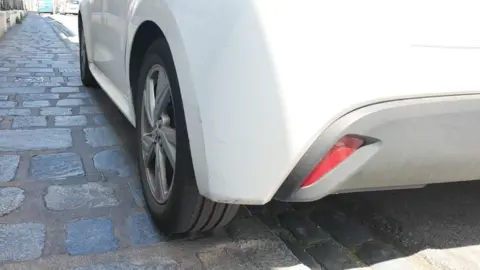 White car mounting a pavement