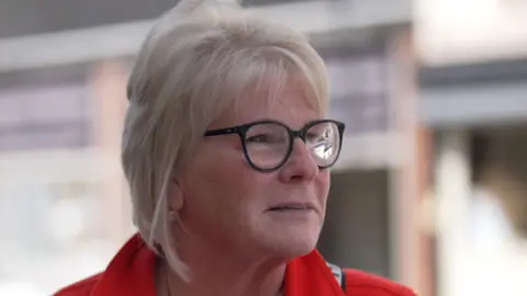 Vanda wearing a red coat and glasses.