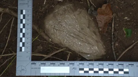 South Wales Police/ CPS The parcel wrapped in brown tape. A square-angled ruler is around it to denote its size