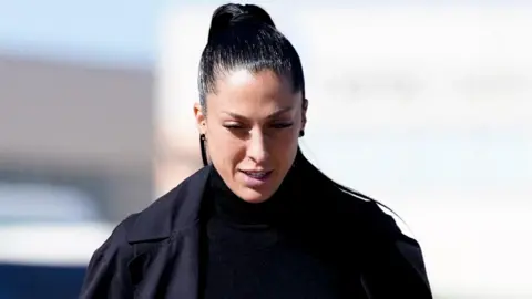 Jenni Hermoso. She is wearing a black coat. Her hair is black and tied up into a high ponytail.