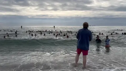 Dave Hitchcock stood on the beach looking out to sea as 100 swimmers join Ruth for her 365th swim