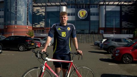 Ethan standing outside Hampden with his bike