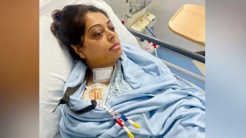 Hafsa Begum A 45-year-old woman is lying in a hospital bed next to a dialysis machine. She is wrapped in a blanket and looks very unwell. She has a number of tubes coming out of her chest area just below her right shoulder.
