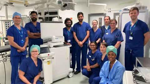 BBC Healthcare staff at Wythenshawe Hospital wearing blue scrubs stood around the new Ion probe technology