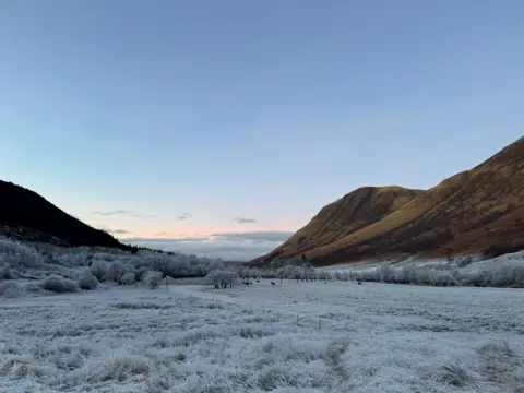 Nicole Browning Fields and hills covered with white frost on a cold day, with a pink sky 
