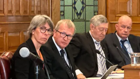 BBC MLCs Dawn Kinnish, Paul Craine, Peter Greenhill and Bill Henderson sitting in the legislative Council listening to evidence.