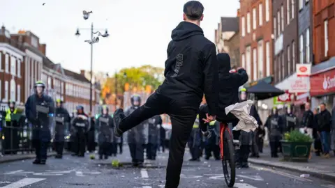 Getty Images Police are seen on Epsom high street as people come out to protest after a woman was raped last Saturday on April 15, 2026 in Epsom.