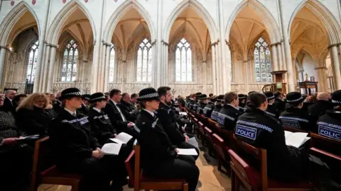 Pet petugas polisi media duduk di bangku di York Minster dengan seragam penuh 