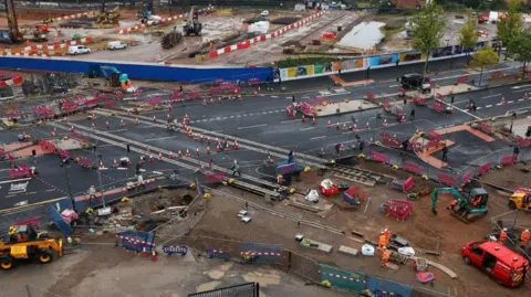 Reuters An aerial view of the HS2 Curzon Street Station site, which shows a range of earth-moving equipment and bollards and barriers can be seen across the site. A group of workers in hi-vis orange suits and wearing protective helmets can be seen in the lower right corner.