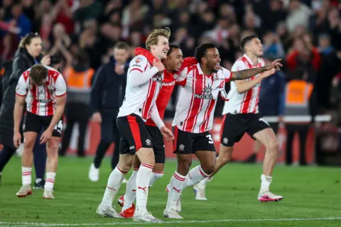 Getty Images Southampton players, wearing a red and white striped strip, celebrate on the pitch. 