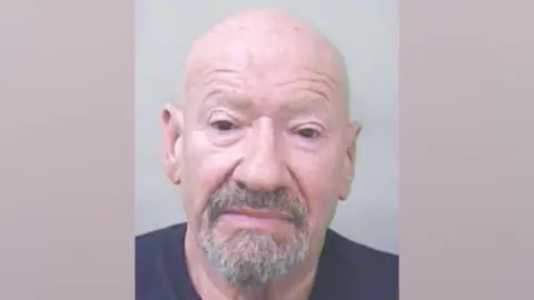 Humberside Police Mugshot showing a old, bald man with a greying goatee beard. He is wearing a navy t-shirt.