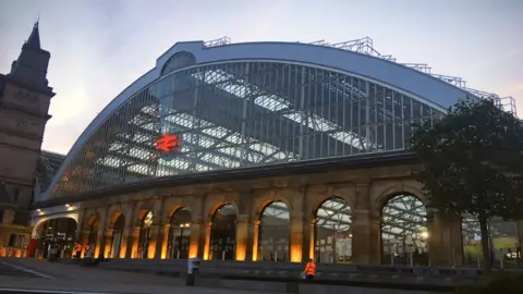 The exterior of Liverpool Lime Street station at dusk with outdoor lights shing on it.