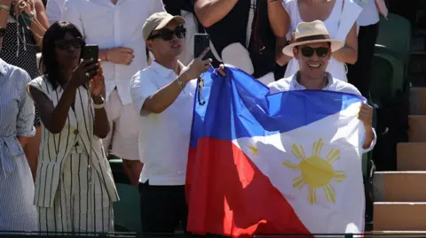 Reuters Two men carry a large Philippine flag in the middle of the crowd at Wimbledon