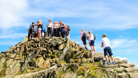 Getty Images Walkers at the summit of Yr Wyddfa on a hot summer's day