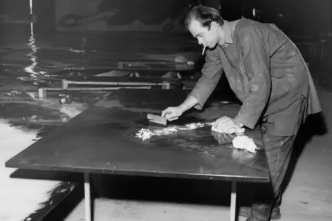 Getty Images Black and white photo of Charles Lutyens leaning over a desk while smoking