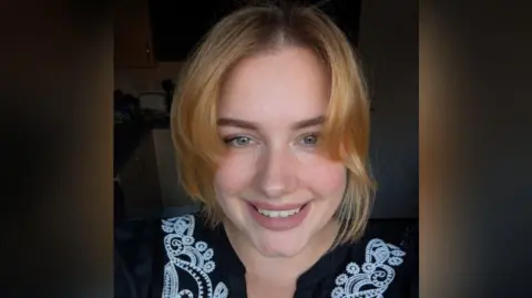 A close up shot of Amber Simmonds, wearing a black blouse with white detail.