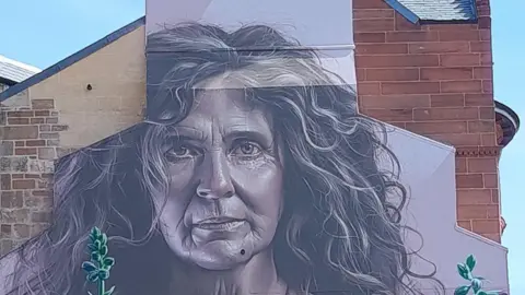 A mural of a woman, painted on the wall of a city building