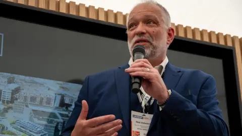 Royal Armouries A man with short grey hair and beard wearing a blue site and white shirt with a lanyard around his neck