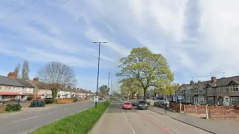 Google A screen shot of Ansty Road in Coventry. The large main road has houses on both sides and a grass verge in the centre. Two cars can be seen on the right hand side of the shot moving towards the camera. 