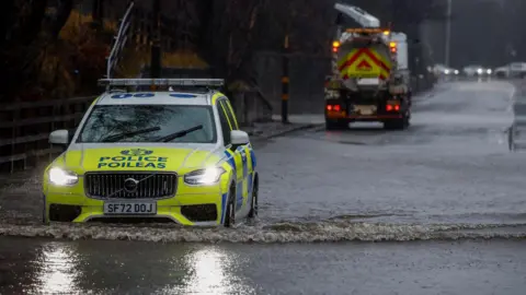 Getty Images A police car drives through a flooded road in the west end of Glasgow
