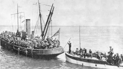 Getty Images A black and white photo showing Allied troops being transported to one of the Dunkirk Little Ships during Operation Dynamo.