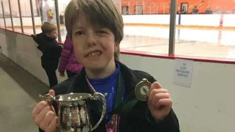 Supplied Callum Mills much younger holding a trophy and a medal smiling at the camera.