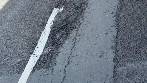 A potholes on a road covered by a white road marking.