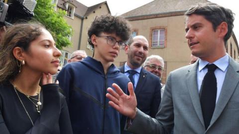 France's Prime Minister Gabriel Attal (R) talks with supporters during a campaign visit in Chatres, centre France, on July 2, 2024, ahead of the second round of France's legislative elections. 