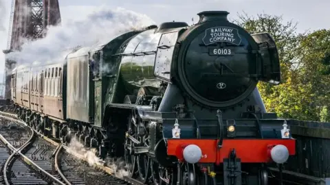 The Flying Scotsman travels towards the camera, with steam emerging from its funnel.