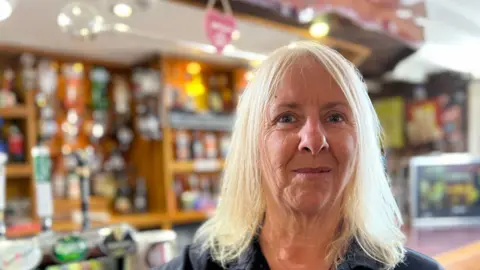 Dawn Dines wearing a black top and standing in front of a bar