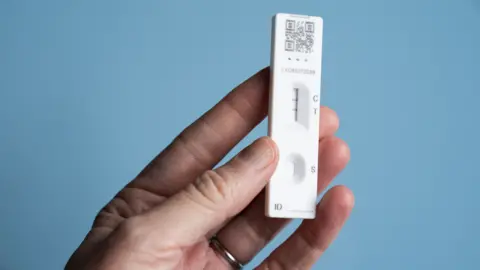 PA Media Hand holds up a positive Covid test, denoted by two fine lines on a test trip