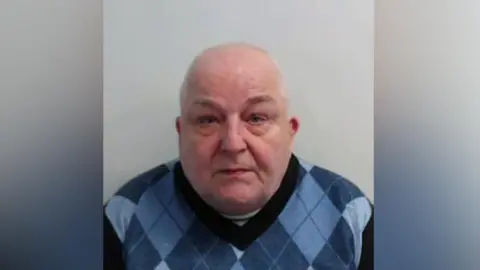 Police Scotland Graham McGill, a bald man in a blue pringle style pullover, stares at the camera in a police mugshot