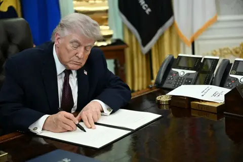 AFP via Getty Images Trump signing an executive order in the Oval Office