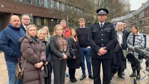 A group of 13 men and women, including Assistant Chief Constable Tony Rowlinson, pose for a photograph in a pedestrianised area outside Portsmouth Crown Court