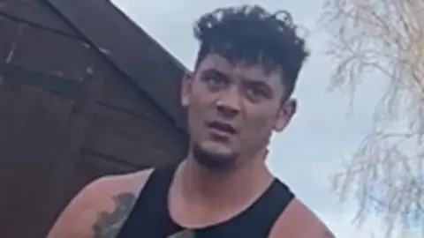 James Knight, a man with short and messy dark hair, is pictured outside wearing a black vest. 