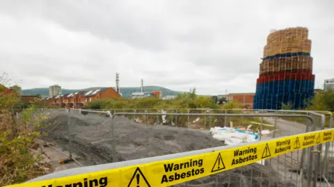 A bonfire behind gates and an asbestos warning 