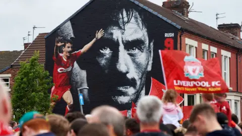 Getty Images A black and white mural of Ian Rush's face on a gable end with Liverpool supporters and flags in front of it