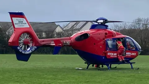 A red and blue air ambulance on a green grass field. 