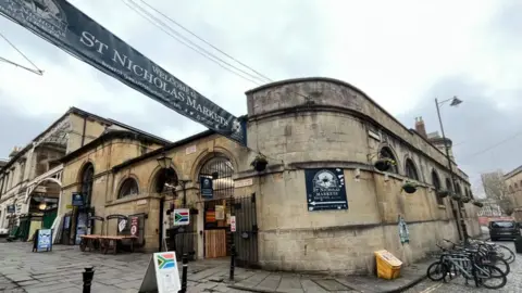 An external view of St Nicholas Markets showing posters and signs advertising the stalls 