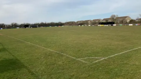 Trowbridge Town FC An image of a football pitch with banners around the outside and a goal at the other end.