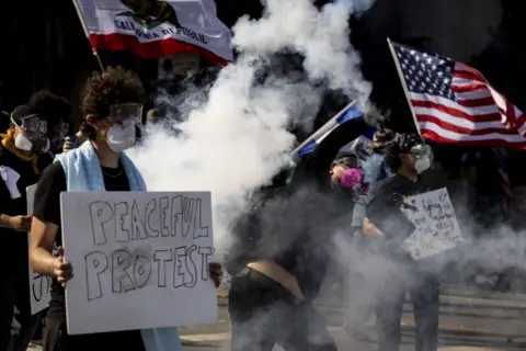 Getty Images A protester in LA throws a tear canister back towards police