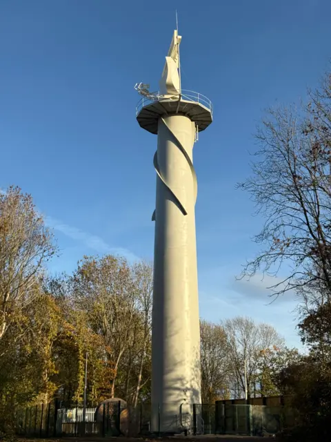 Cranfield University A radar control tower with trees surrounding it and blue sky above.